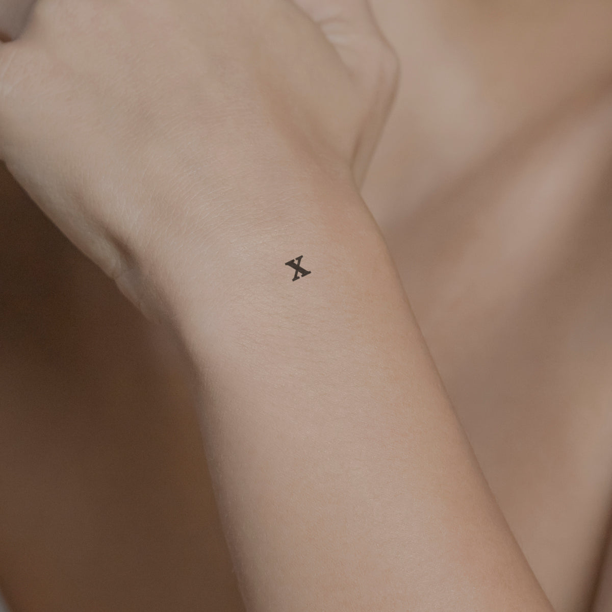 Schriftzug Tattoo Kleinbuchstabe: x von minink, der Marke für temporäre Tattoos.