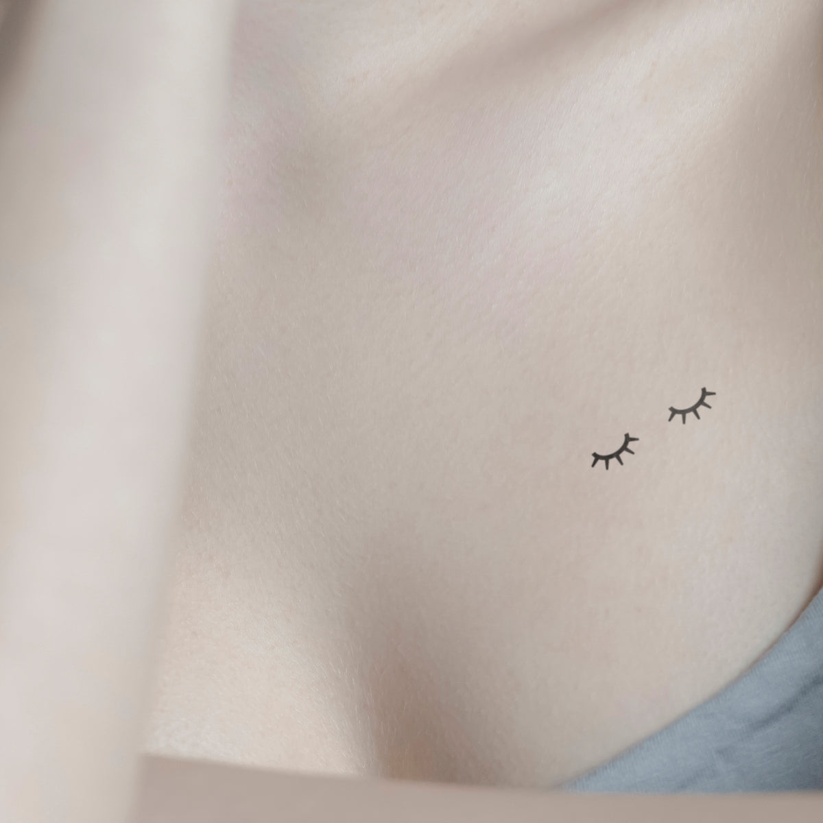 Minimalist star and flower tattoo on the collarbone.