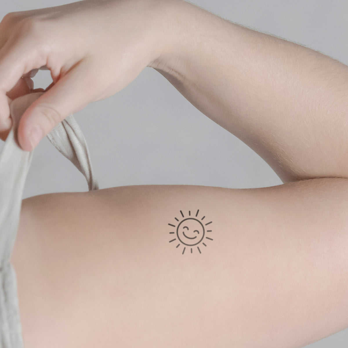 Lächelnde Sonne Tattoo von minink, der Marke für temporäre Tattoos.