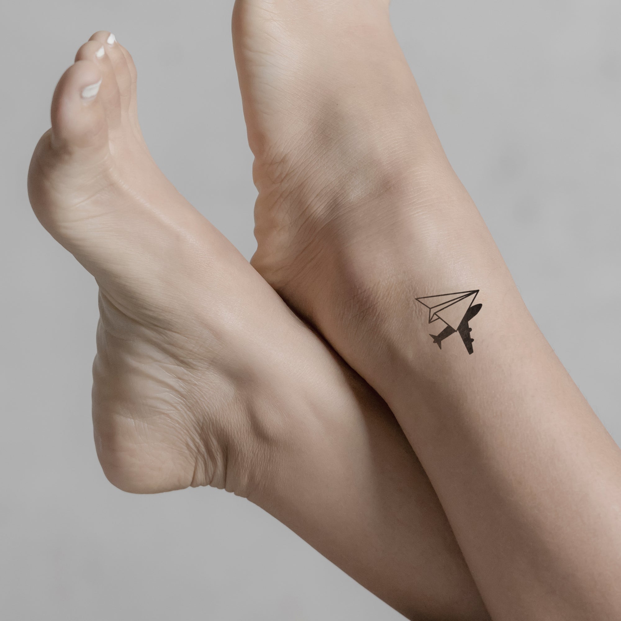 Papierflugzeug mit Flugzeugschatten Tattoo von minink, der Marke für temporäre Tattoos.